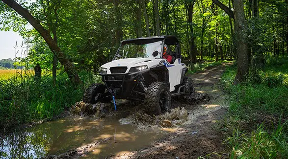 A rider in a 2027 Polaris GENERAL XP 1000 side-by-side driving through the mud.