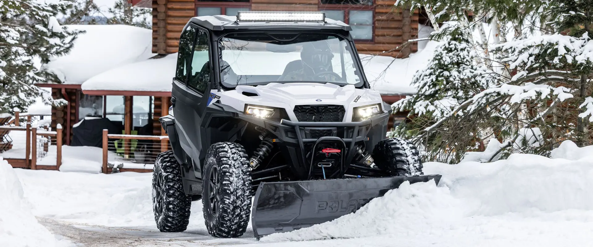 A rider in a 2027 Polaris GENERAL XP 1000 side by side plowing snow.