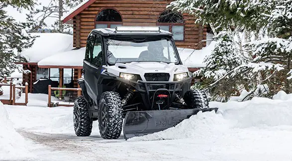 A rider in a 2027 Polaris GENERAL XP 1000 side by side plowing snow.
