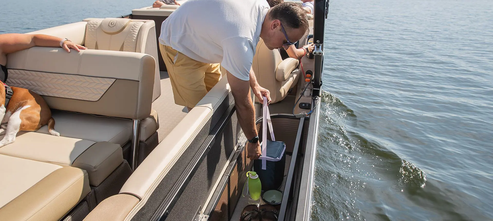 Man using the under-seat storage on a Godfrey Monaco Lounge pontoon boat.