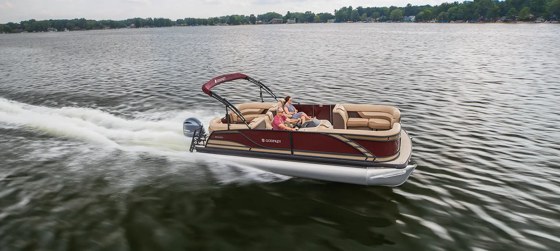 couple relaxing while speeding across a lake on a godfrey monaco split bench pontoon