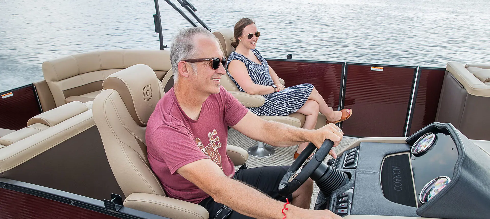 couple sitting in the co-captain's chairs on a godfrey monaco split bench pontoon