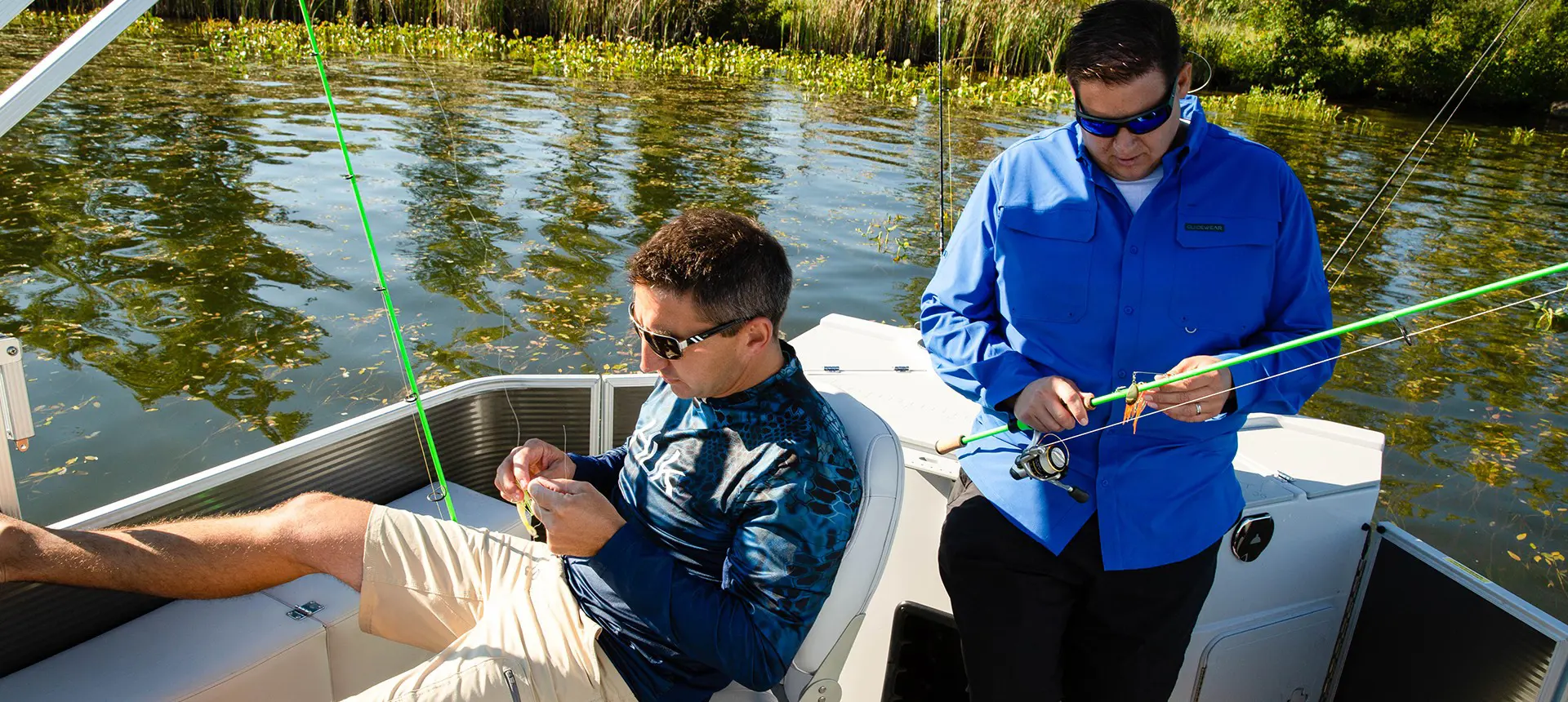 2 hommes préparant leurs cannes à pêche à bord d’un ponton sweetwater fishing
