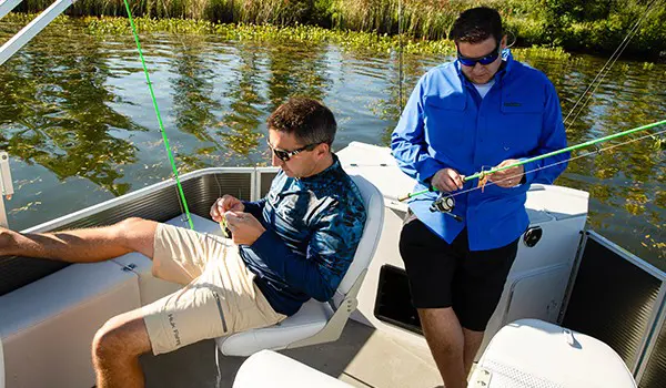 2 hommes préparant leurs cannes à pêche à bord d’un ponton sweetwater fishing