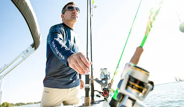 homme saisissant le poteau des porte-cannes intégrés sur un ponton godfrey Sweetwater Fishing