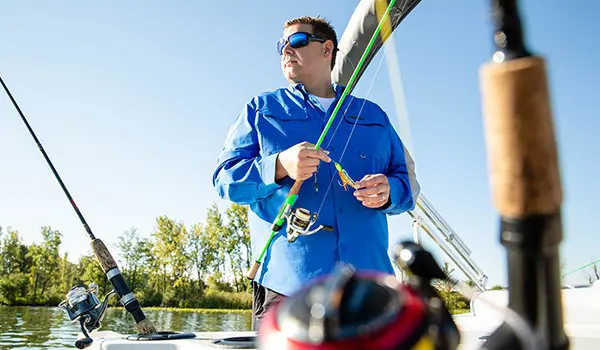 homme mettant un appât tournant sur sa canne à pêche sur un ponton godfrey sweetwater fishing