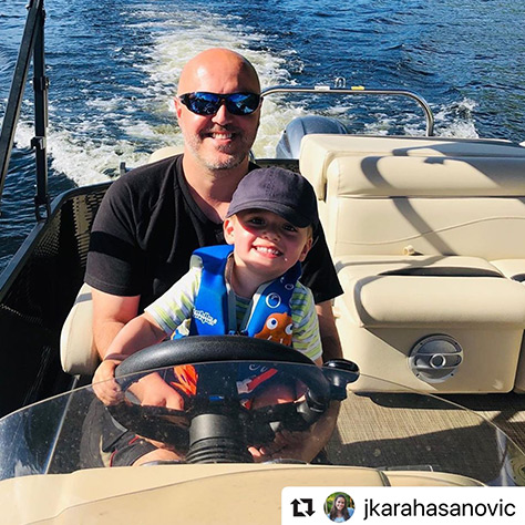 Man driving a boat with son on his lap