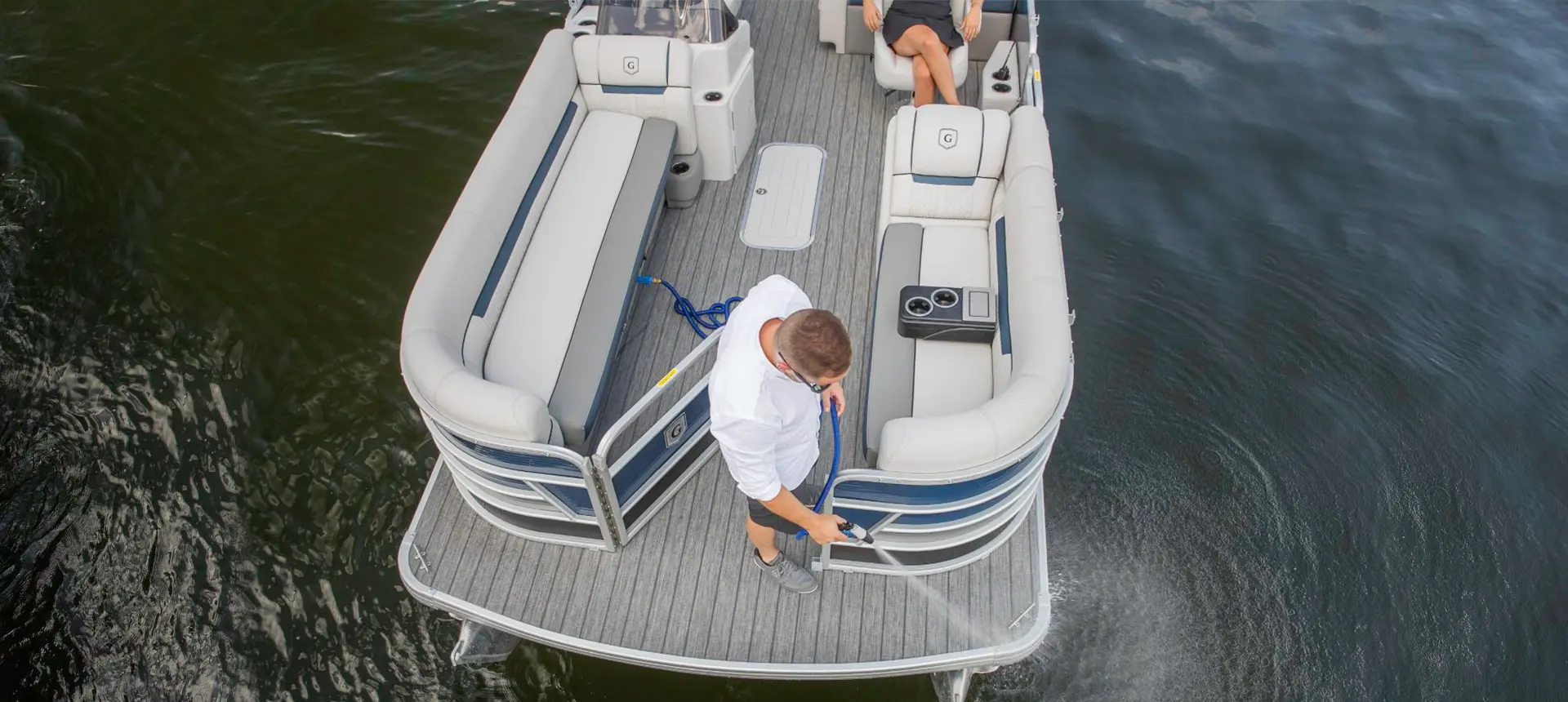 man using the washdown system on a godfrey sweetwater entertainment pontoon
