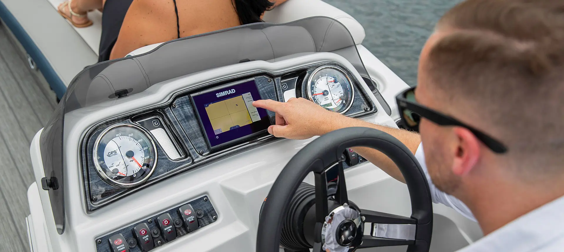 man using sitting at the redesigned helm on a godfrey sweetwater entertainment pontoon