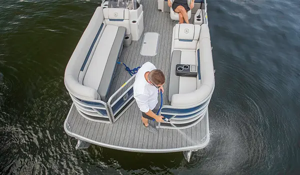 man using the washdown system on a godfrey sweetwater entertainment pontoon