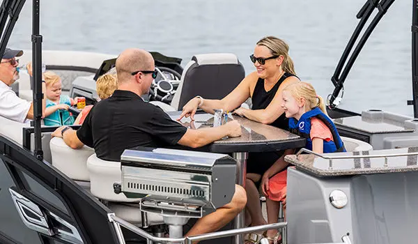 family sitting at the table on a godfrey aquapatio entertainment pontoon