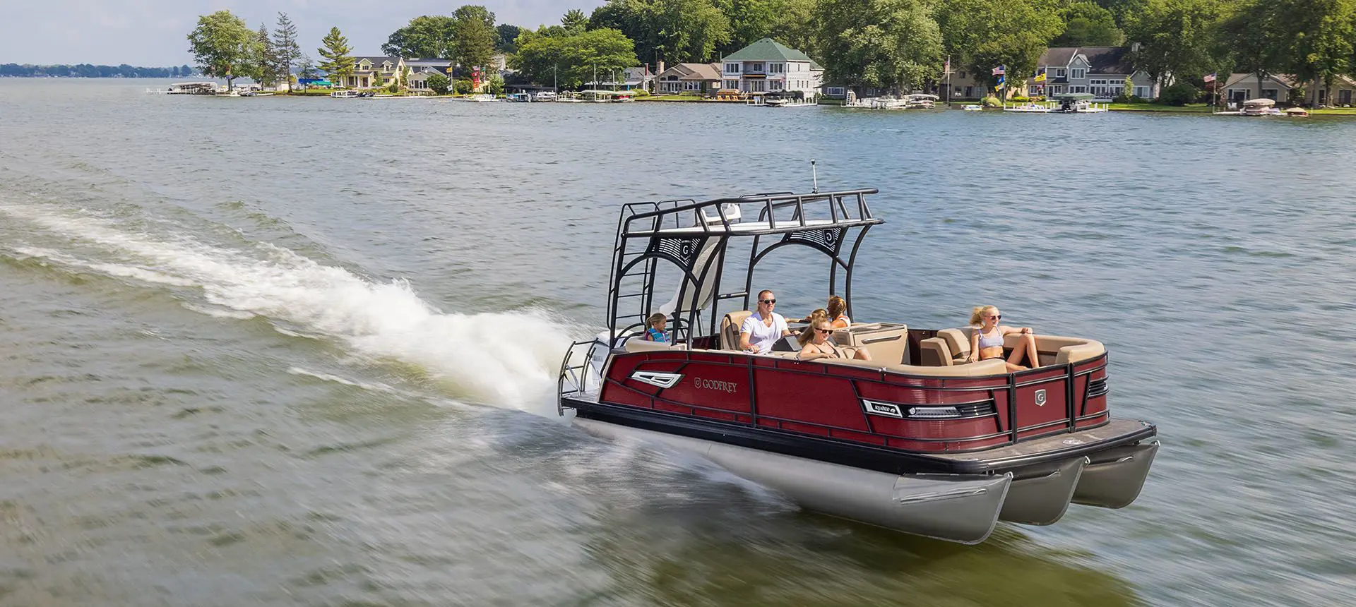 godfrey aquapatio sundeck pontoon speeding across a lake