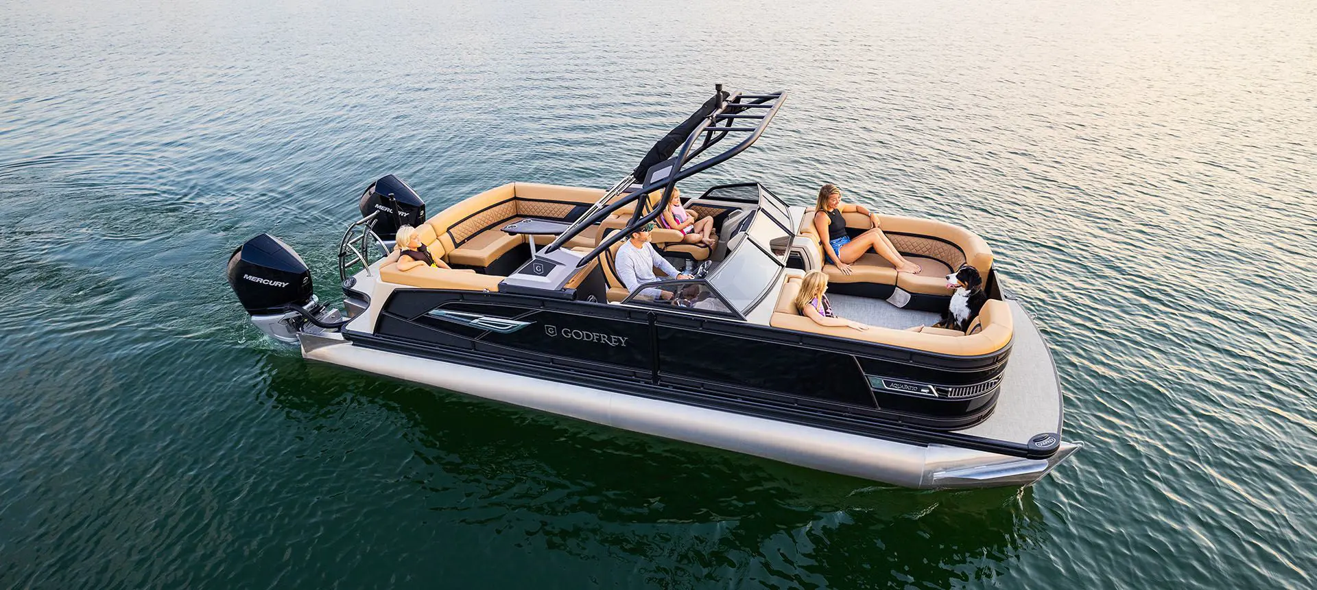 side view of a godfrey aquapatio winshield twin tritoon cruising on a lake