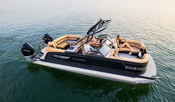 side view of a godfrey aquapatio winshield twin tritoon cruising on a lake