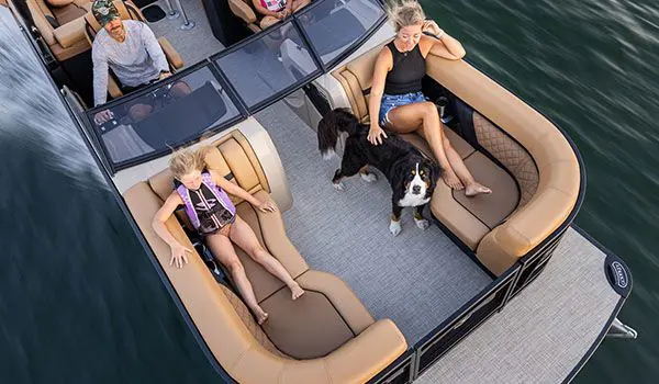 girls relaxing with their dogs on the split bench seats on a godfrey aquapatio winshield pontoon