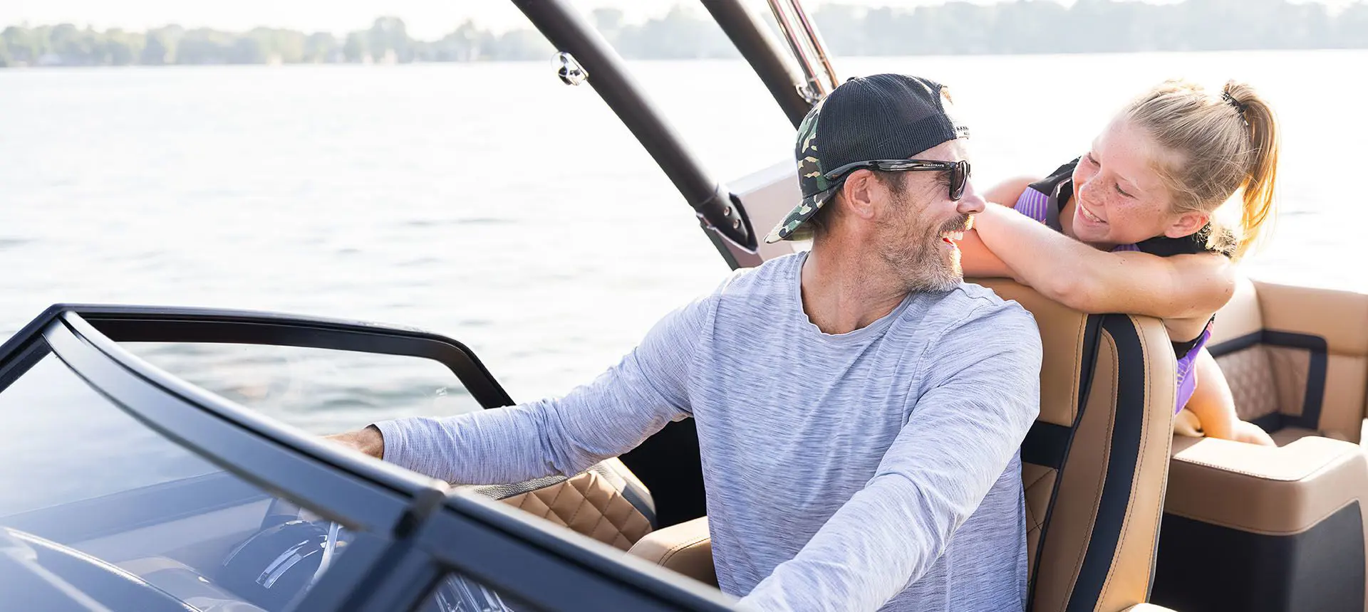 dad sitting at the helm and smiling at his daughter on a godfrey aquapatio winshield pontoon