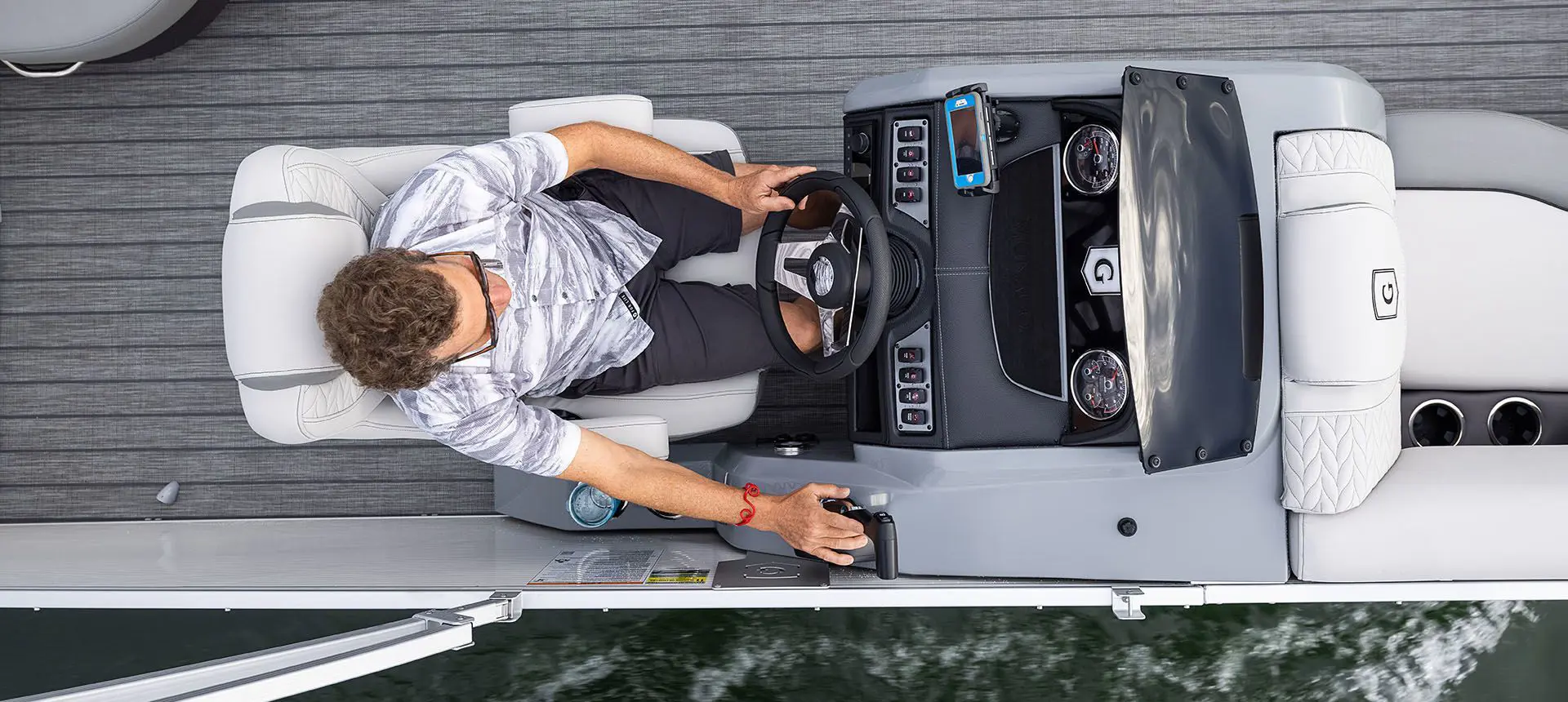man sitting at the driving console on the godfrey monaco cruise pontoon