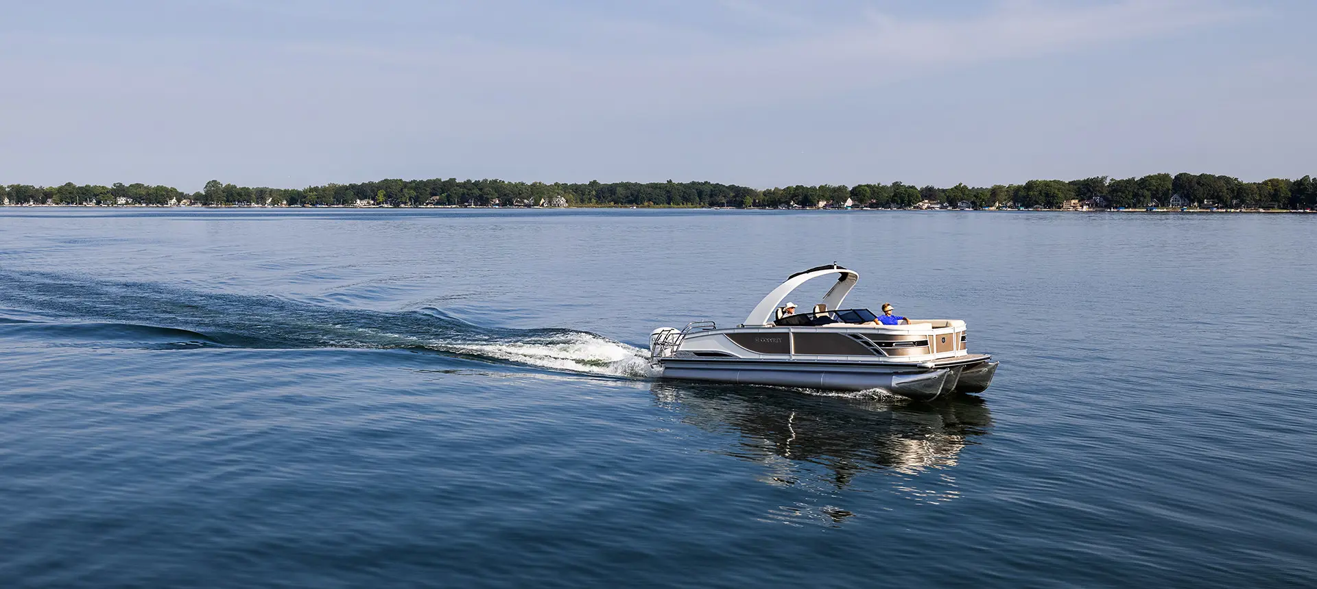 side profile of a godfrey sanpan windshield pontoon cruising on a lake