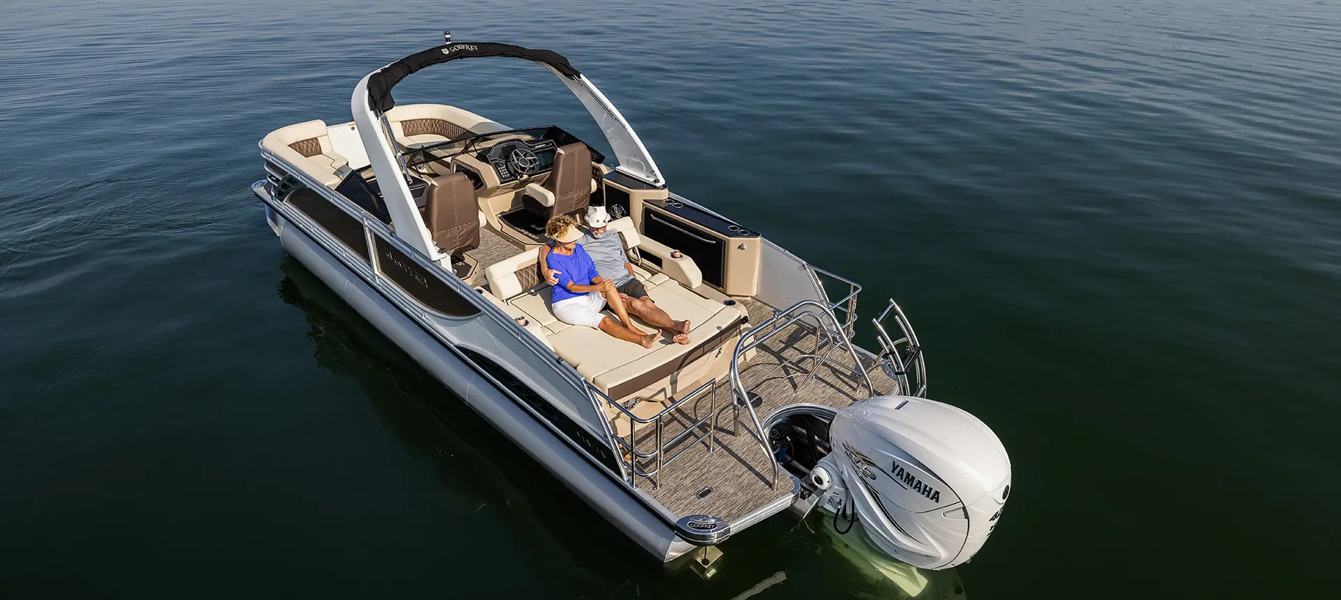 couple sitting comfortably on the stern swingback seat on a godfrey sanpan windshield pontoon