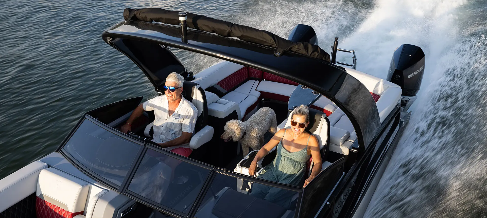 couple smiling with their dog on a godfrey sanpan windshield pontoon