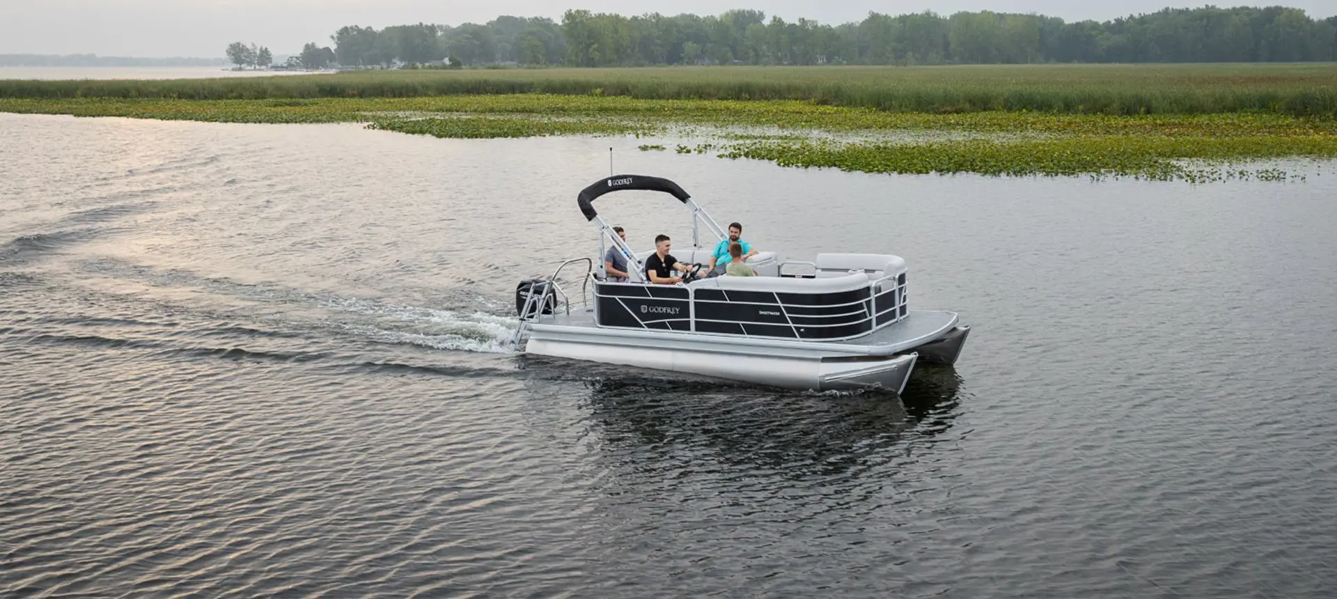 friends driving on a lake in their godfrey xperience cruise pontoon