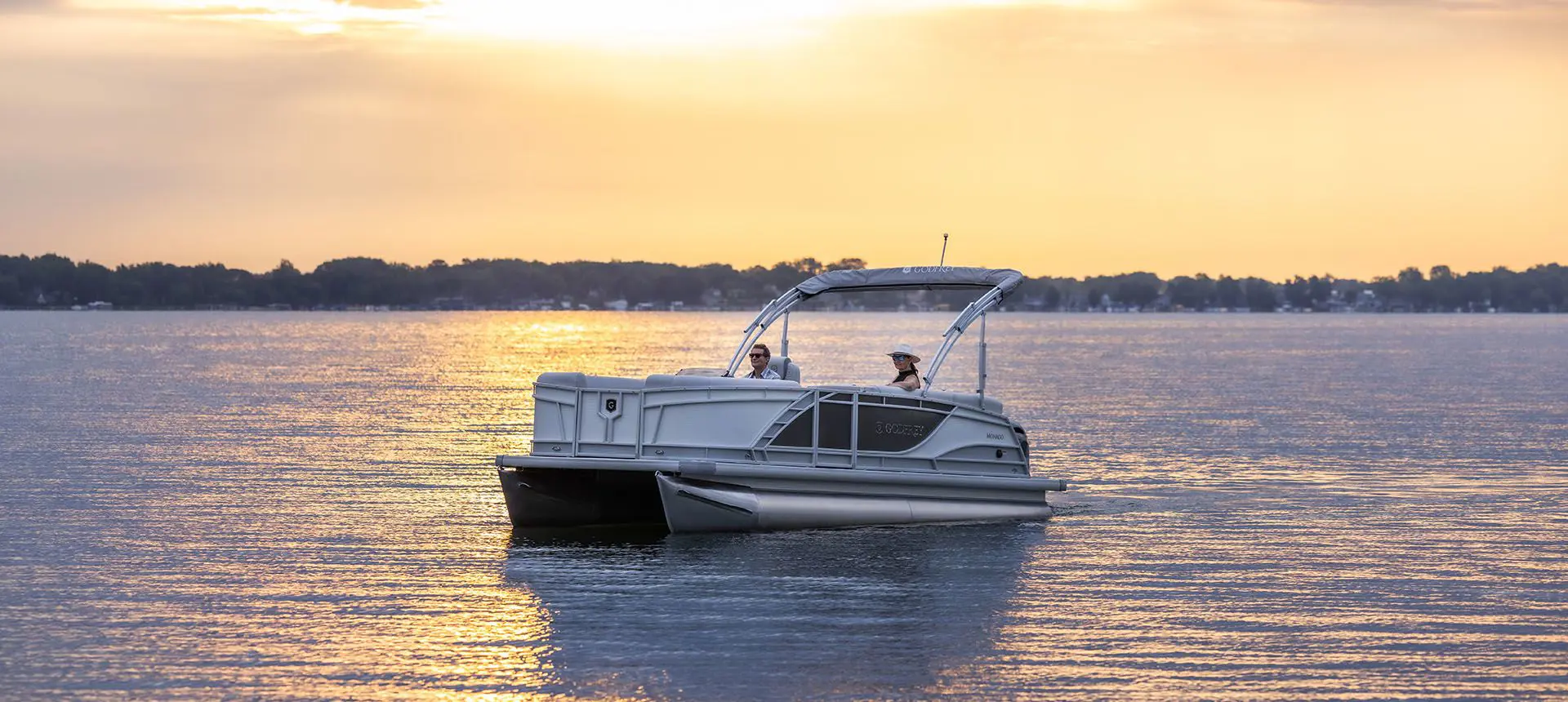 godfrey monaco series pontoon floating on a lake at sunset