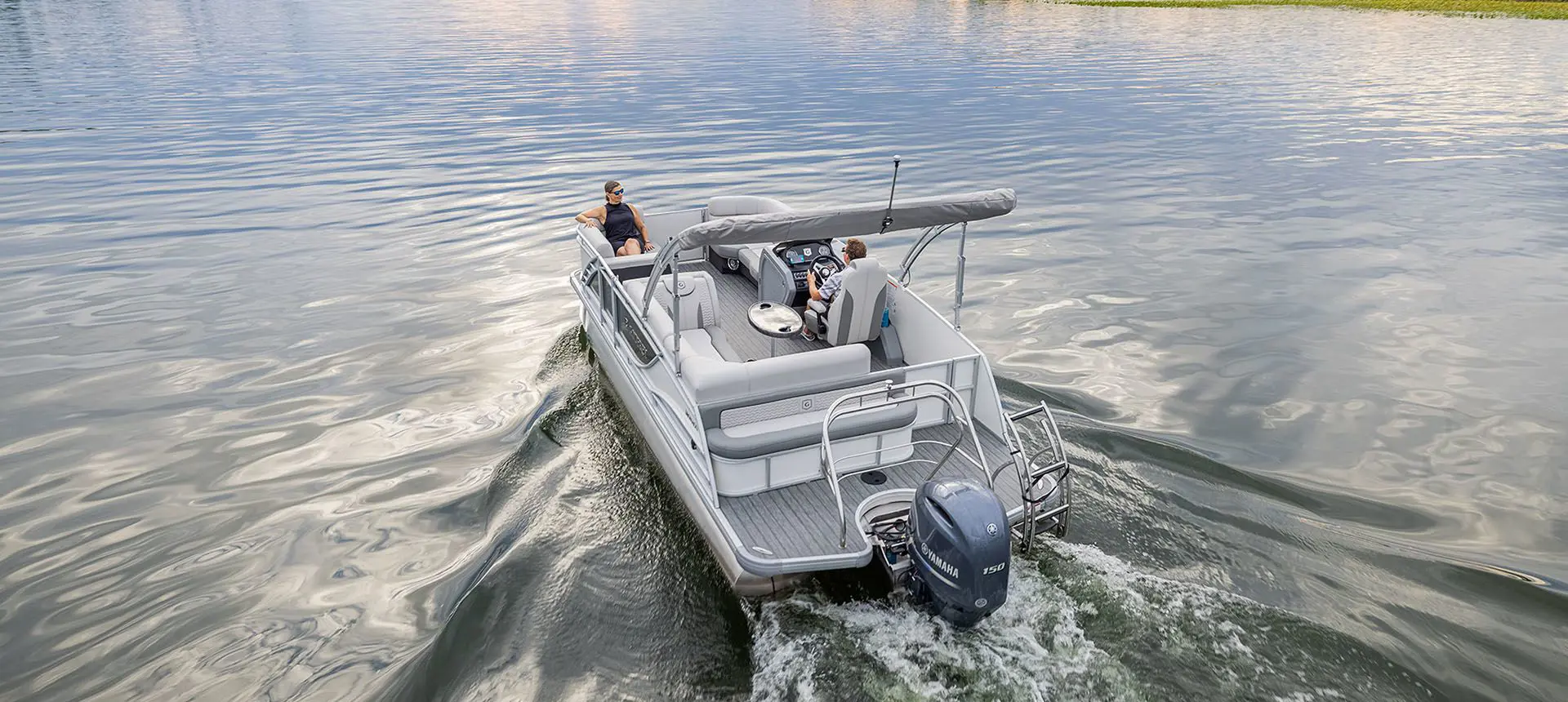 rear view of a godfrey monaco series pontoon cruising on a lake