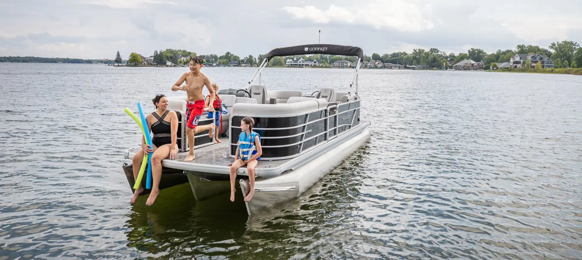 family sitting on the bow of a godfrey xperience split bench tritoon