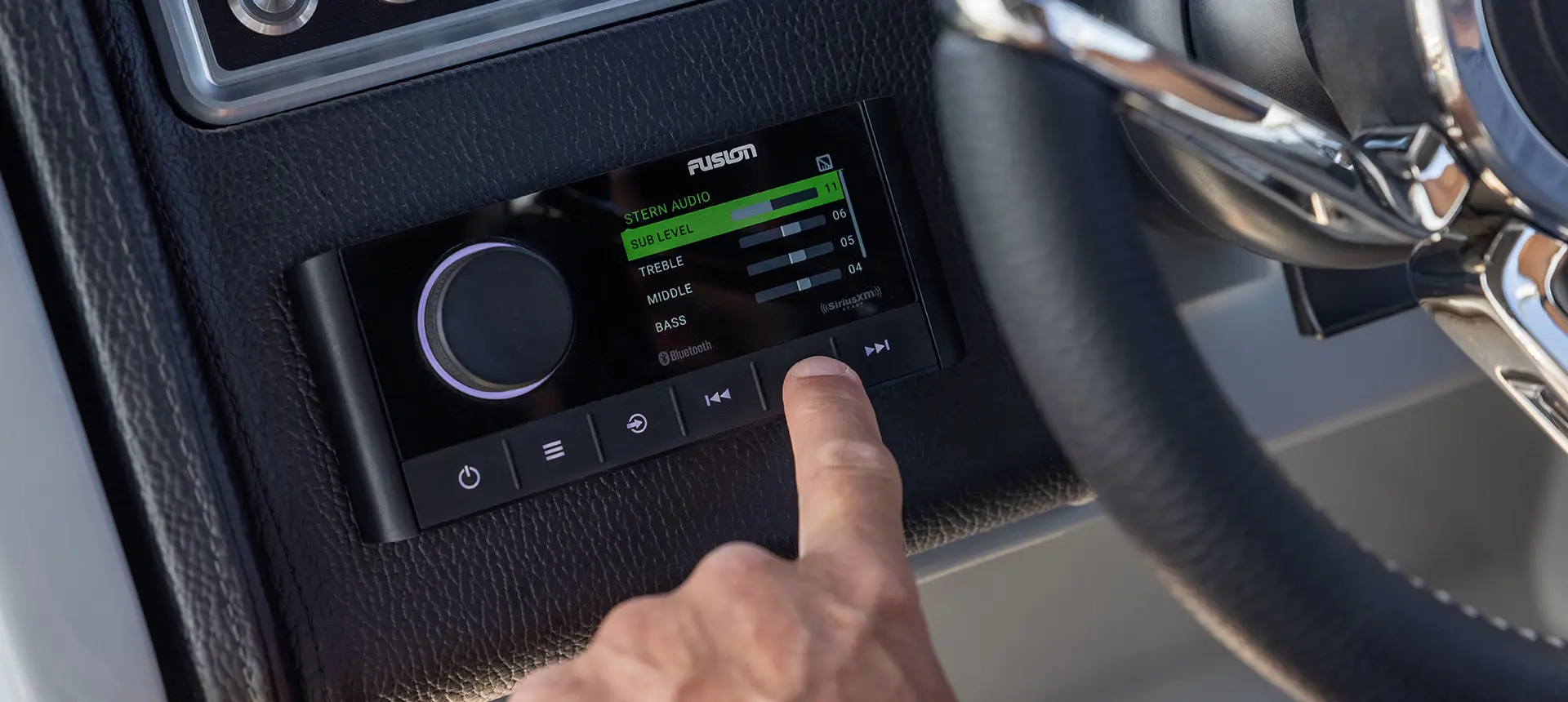 Man pointing to the fusion audio system on the helm of a Godfrey AquaPatio Entertainment pontoon boat.