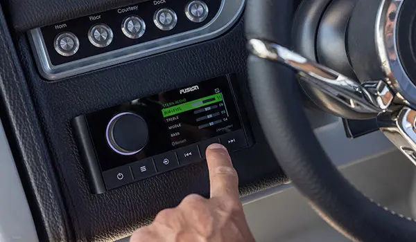 man pointing to the fusion audio system on the helm of a godfrey aquapatio entertainment pontoon