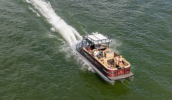 family relaxing on a godfrey aquapatio sundeck pontoon while driving across a lake