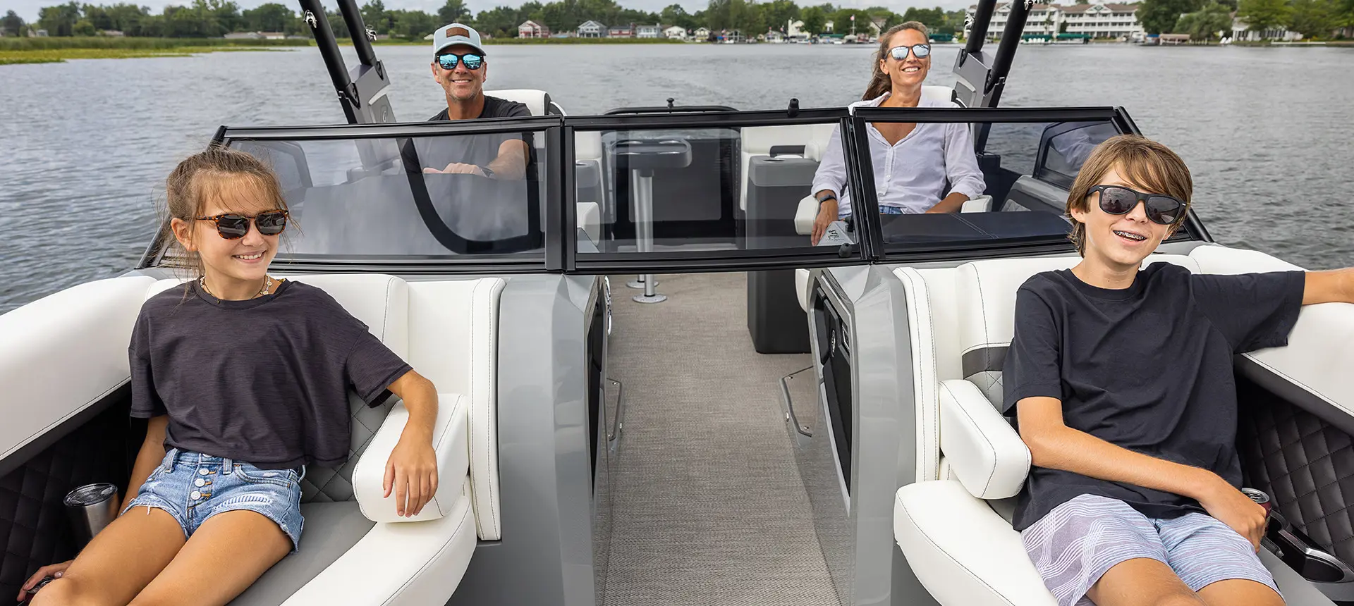 family smiling while cruising a lake on a godfrey aquapatio winshield pontoon
