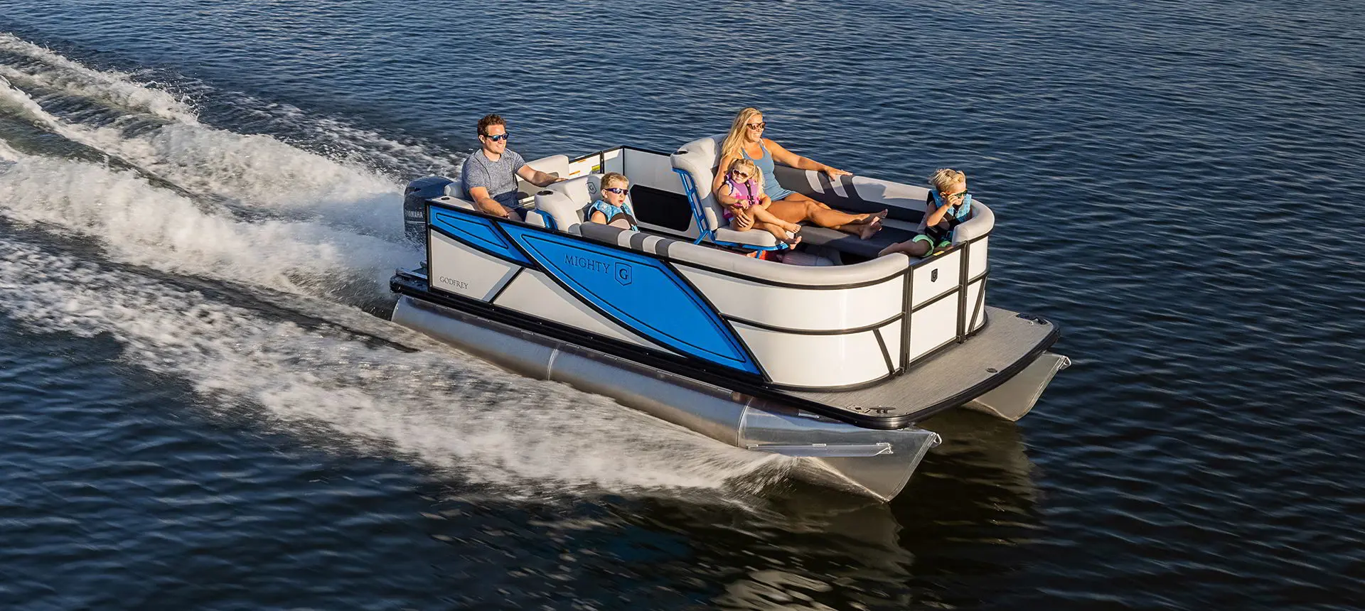 Family relaxing on a Godfrey Mighty G Cruise pontoon boat while cruising a lake.