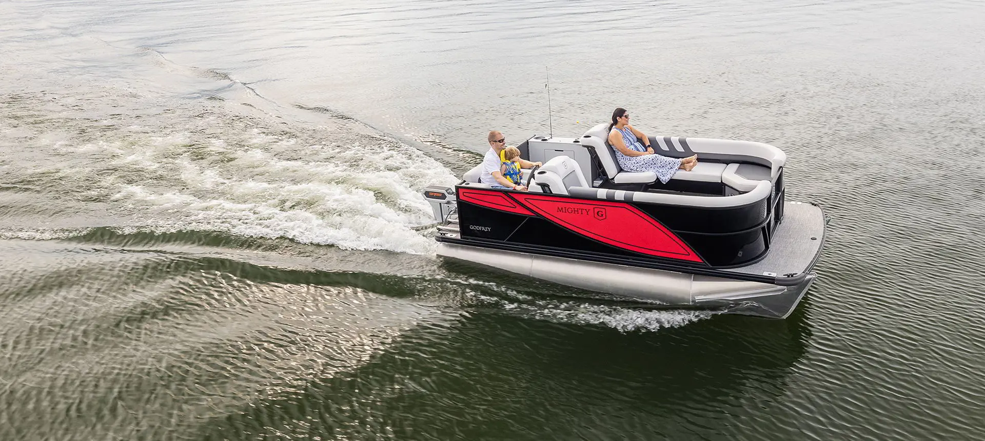 Side view of a Godfrey Mighty G Cruise pontoon boat on a lake.
