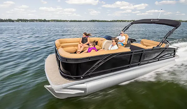 family sitting on the bow split bench seats while dad sits at the helm driving a godfrey monaco lounge pontoon