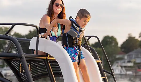 mom helping son down the slide on a godfrey monaco sundeck pontoon