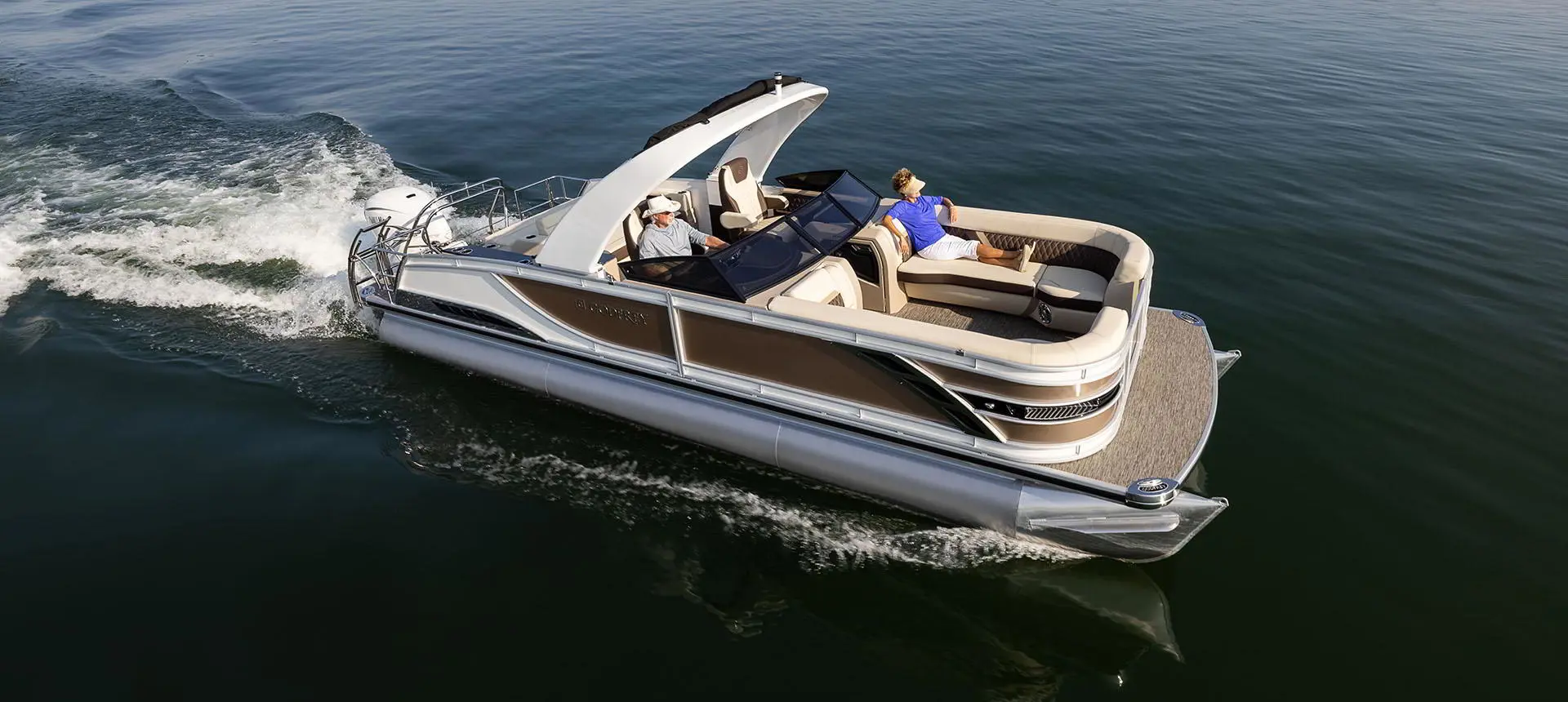 side view of a godfrey sanpan lounge pontoon cruising on a lake