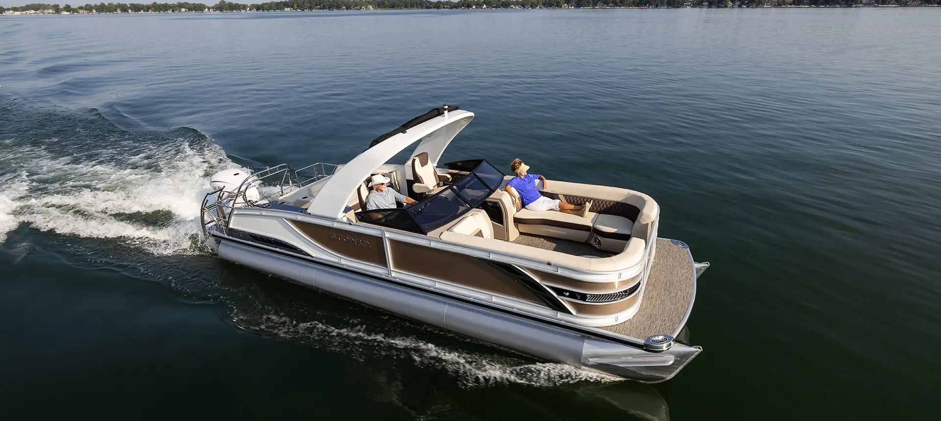 side view of a godfrey sanpan lounge pontoon cruising on a lake