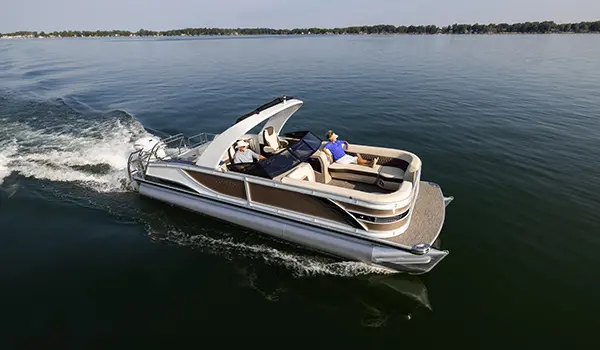 side view of a godfrey sanpan lounge pontoon cruising on a lake