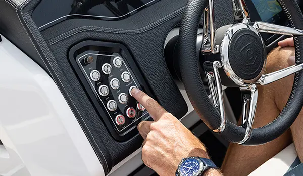 Man pressing a button on the helm of a Godfrey Sanpan Twin tritoon.