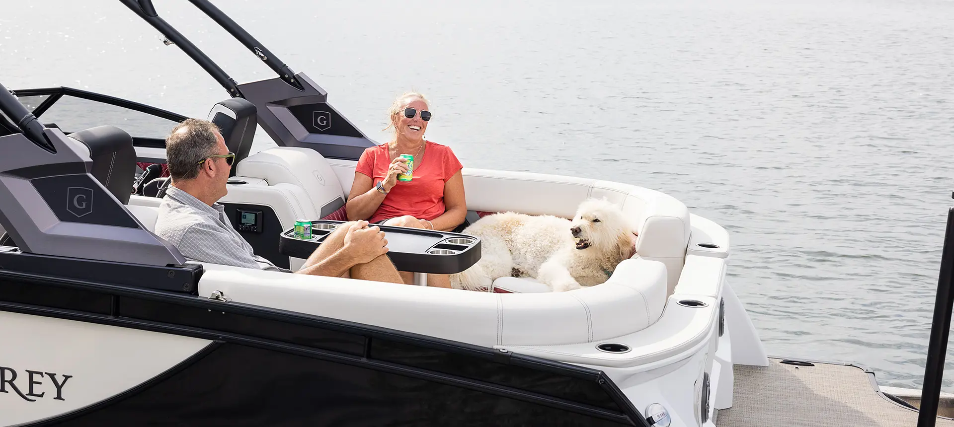 Couple and their dog relaxing on the bow split bench seat on a Godfrey Sanpan Twin tritoon.