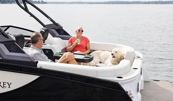 Couple and their dog relaxing on the bow split bench seat on a Godfrey Sanpan Twin tritoon.