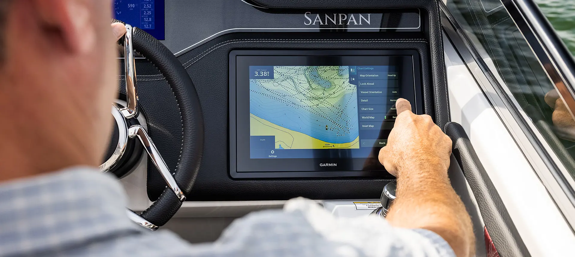 Man using the Garmin GPS at the helm on a Godfrey Sanpan Twin tritoon.