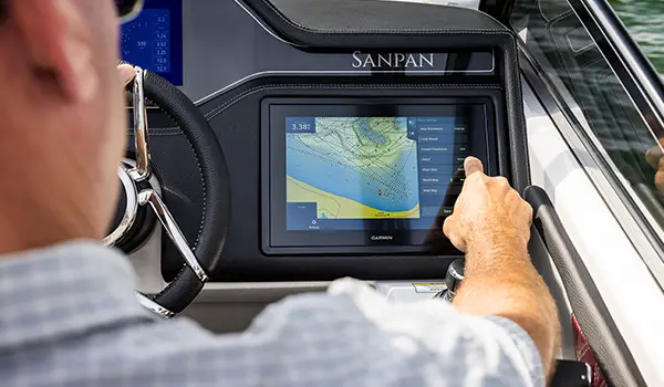Man using the Garmin GPS at the helm on a Godfrey Sanpan Twin tritoon.