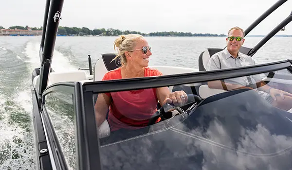 Femme à la barre pilotant un ponton Godfrey Sanpan Windshield.