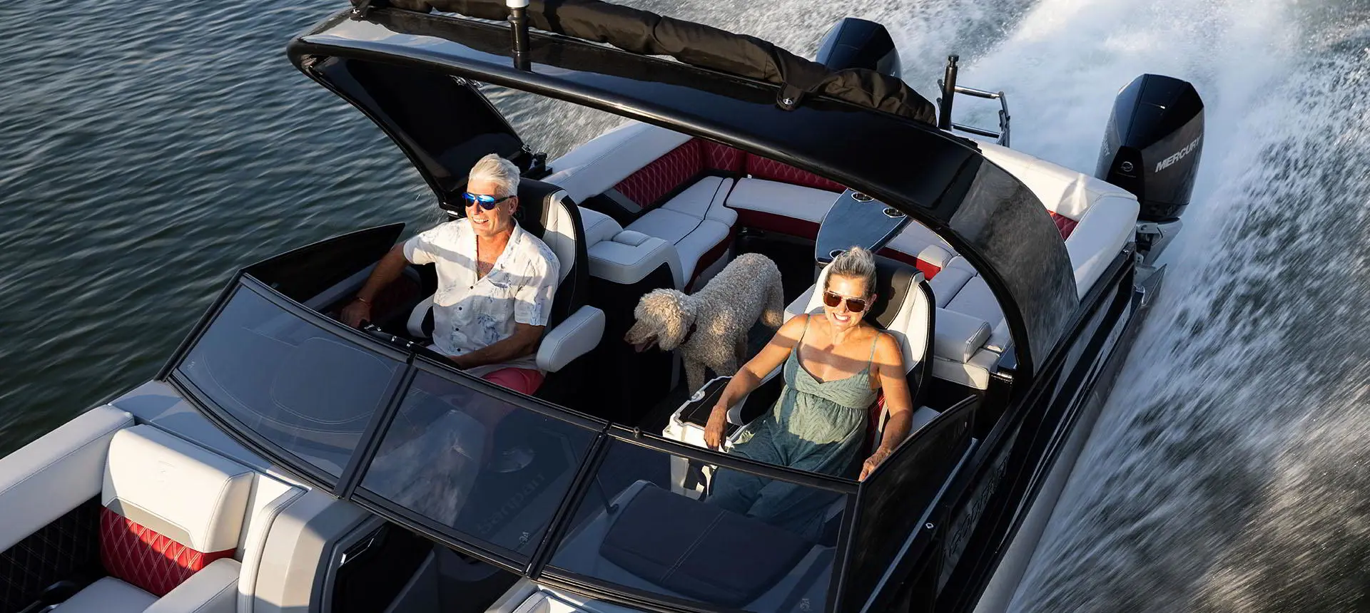 Couple souriant avec leur chien à bord d’un ponton Godfrey Sanpan Windshield.