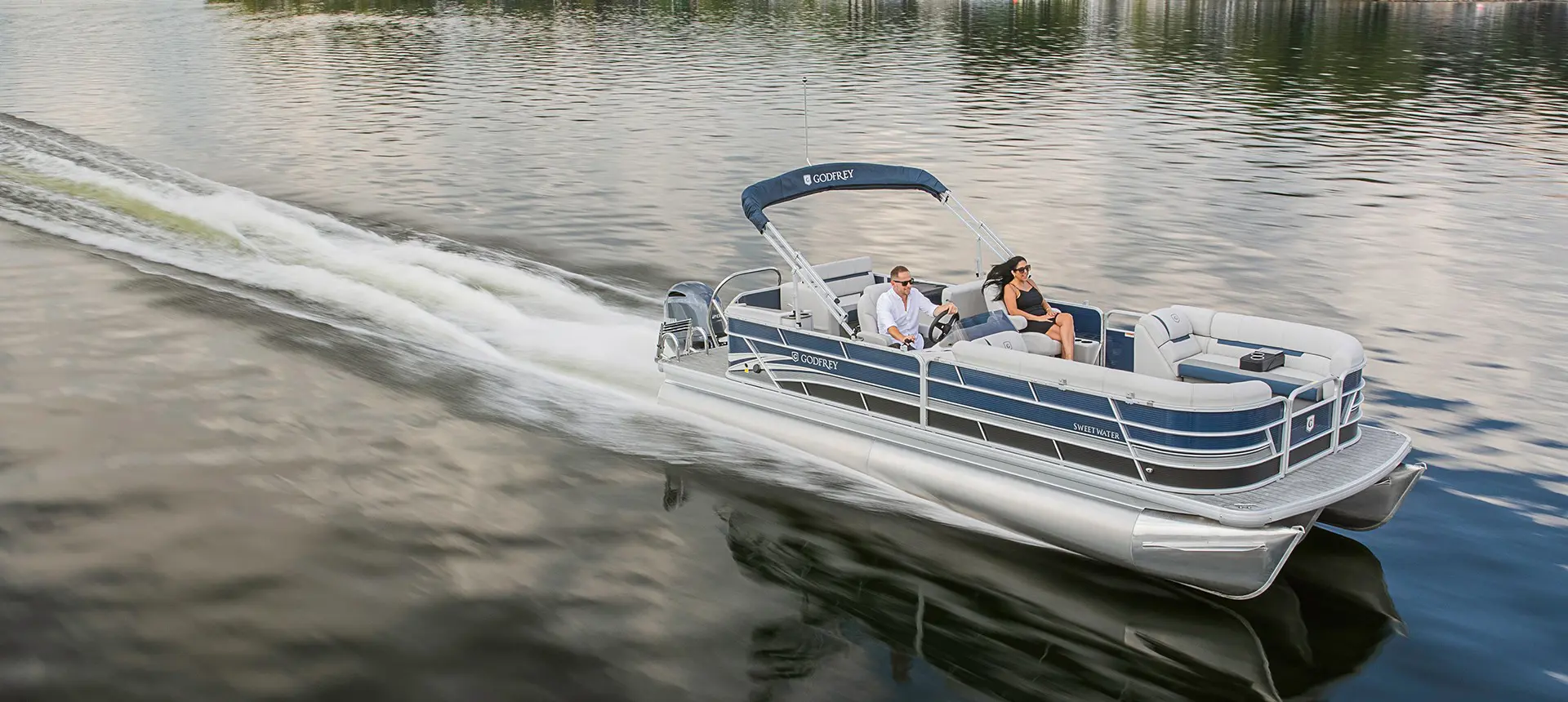couple cruising across the lake on a godfrey sweetwater entertainment pontoon