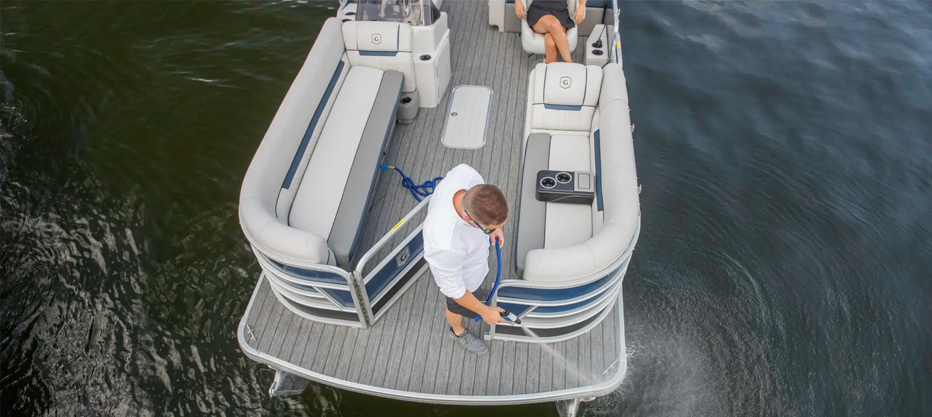 man spraying down the bow of a godfrey sweetwater entertainment pontoon