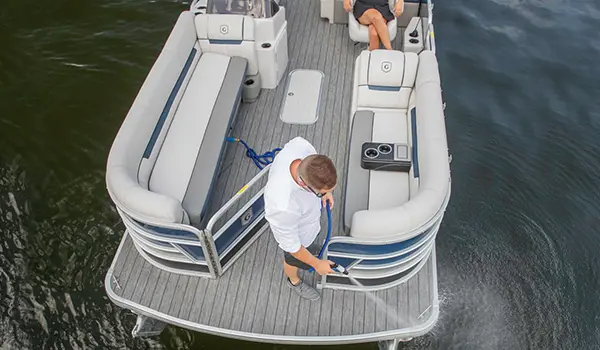 man spraying down the bow of a godfrey sweetwater entertainment pontoon