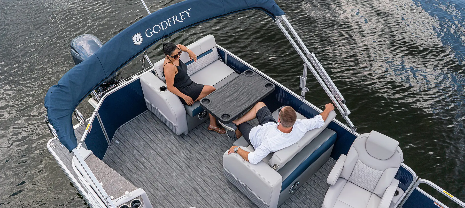 couple relaxing at the stern table on a godfrey sweetwater entertainment pontoon